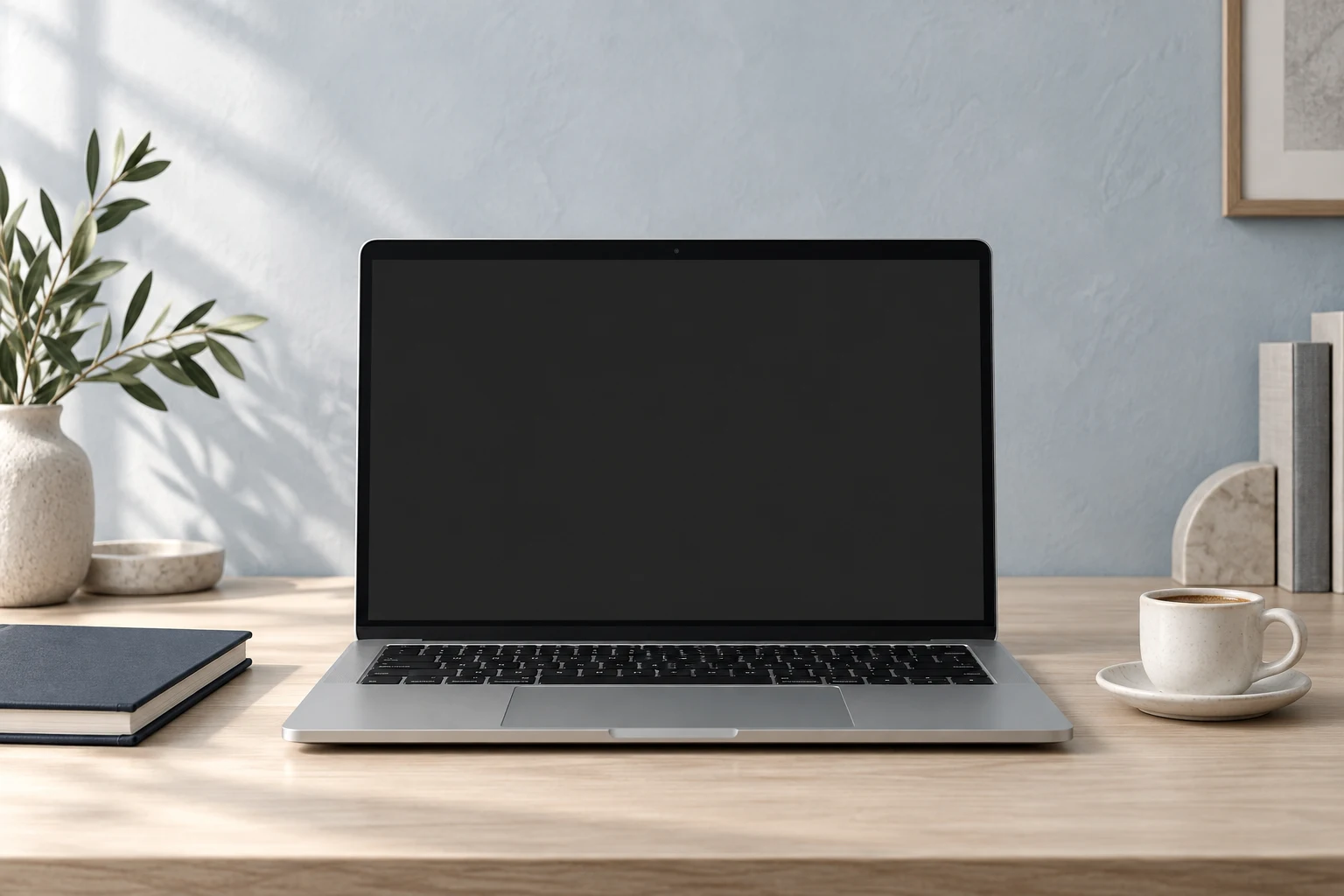 Silberner Laptop auf einem hellen Schreibtisch neben einer Tasse Kaffee
